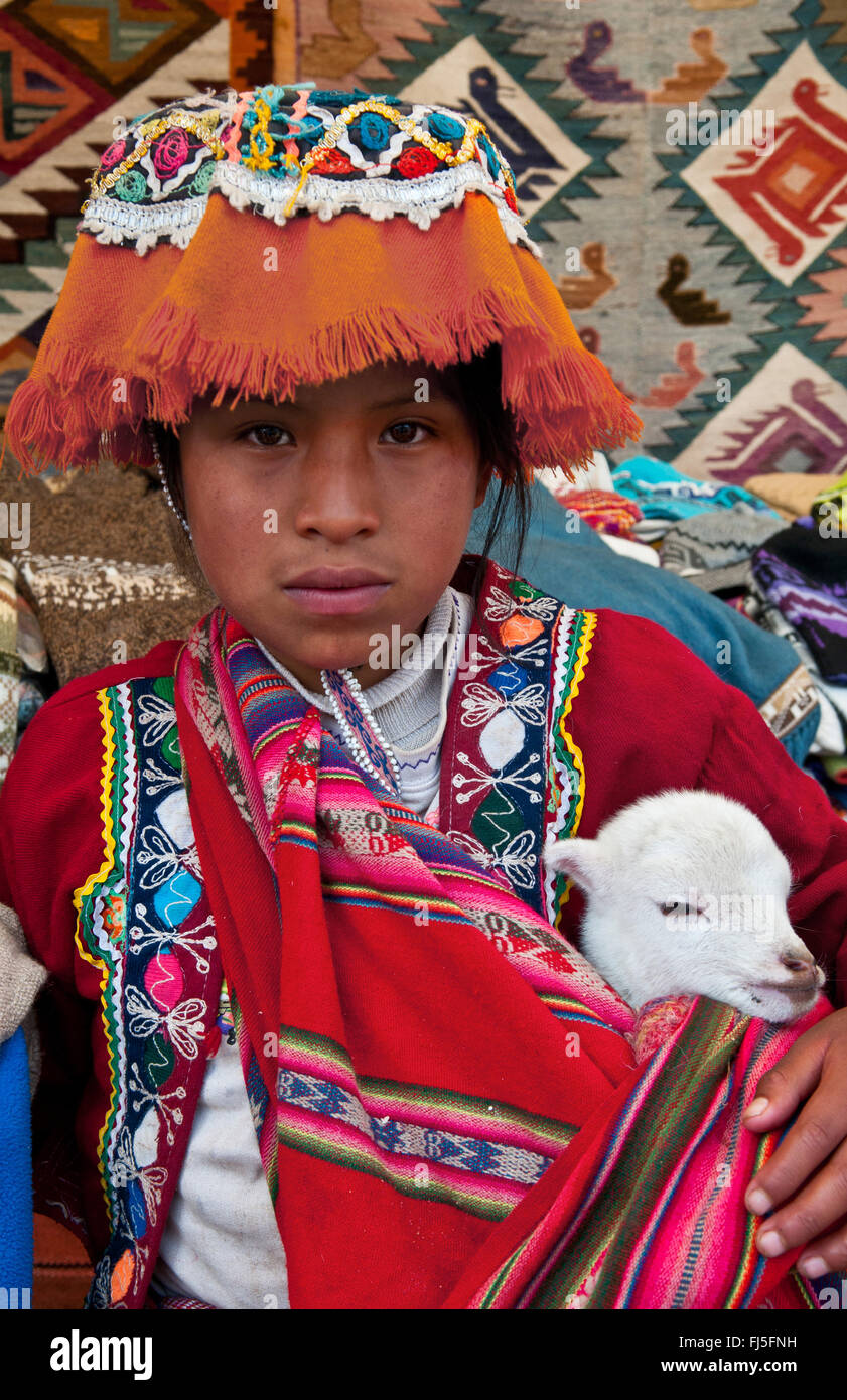 Fille en vêtements traditionnels colorés avec un lama bébé sur son bras, portrait d'un enfant, le Pérou, Pisaq Banque D'Images