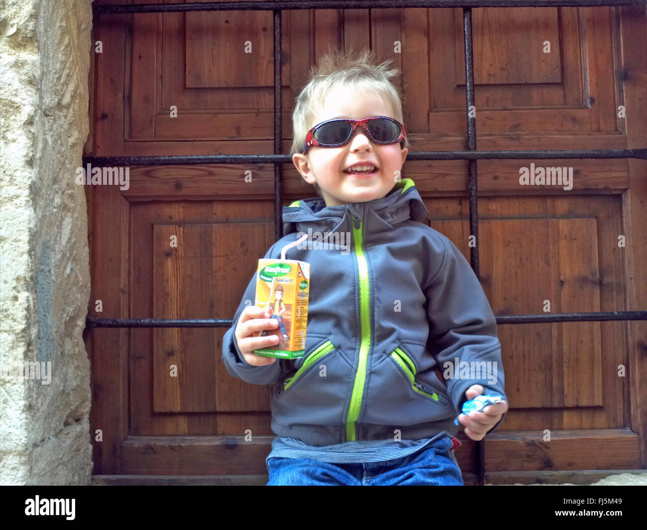 Cool garçon avec des lunettes de la tenue d'une boîte de jus à la main, Allemagne Banque D'Images