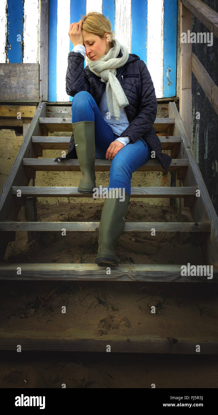 Sad young woman sitting on stairs cabine de plage Banque D'Images