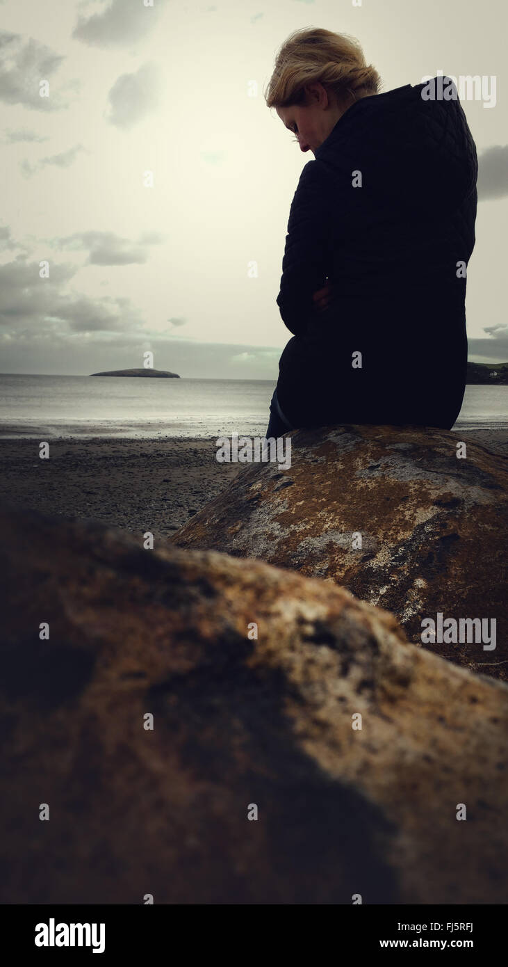 Femme debout sur la plage par la roche Banque D'Images