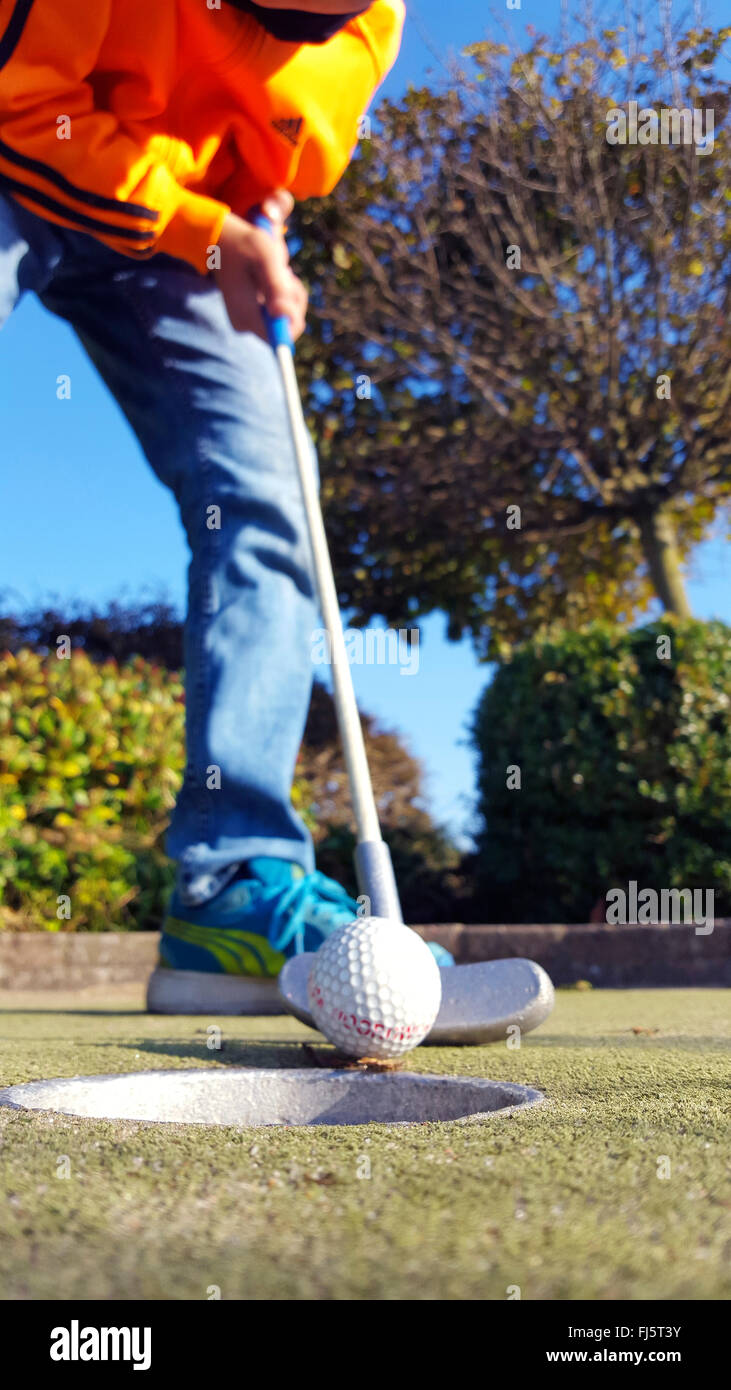 Mini-golf, mini-golf ball est troué par un garçon, Allemagne Banque D'Images