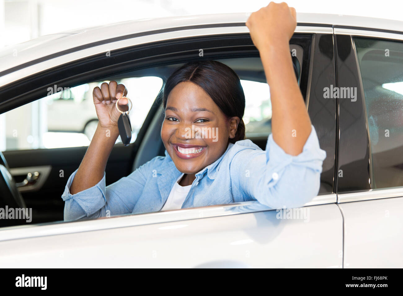 Cheerful young African woman montrant sa nouvelle clé de voiture chez le concessionnaire Banque D'Images