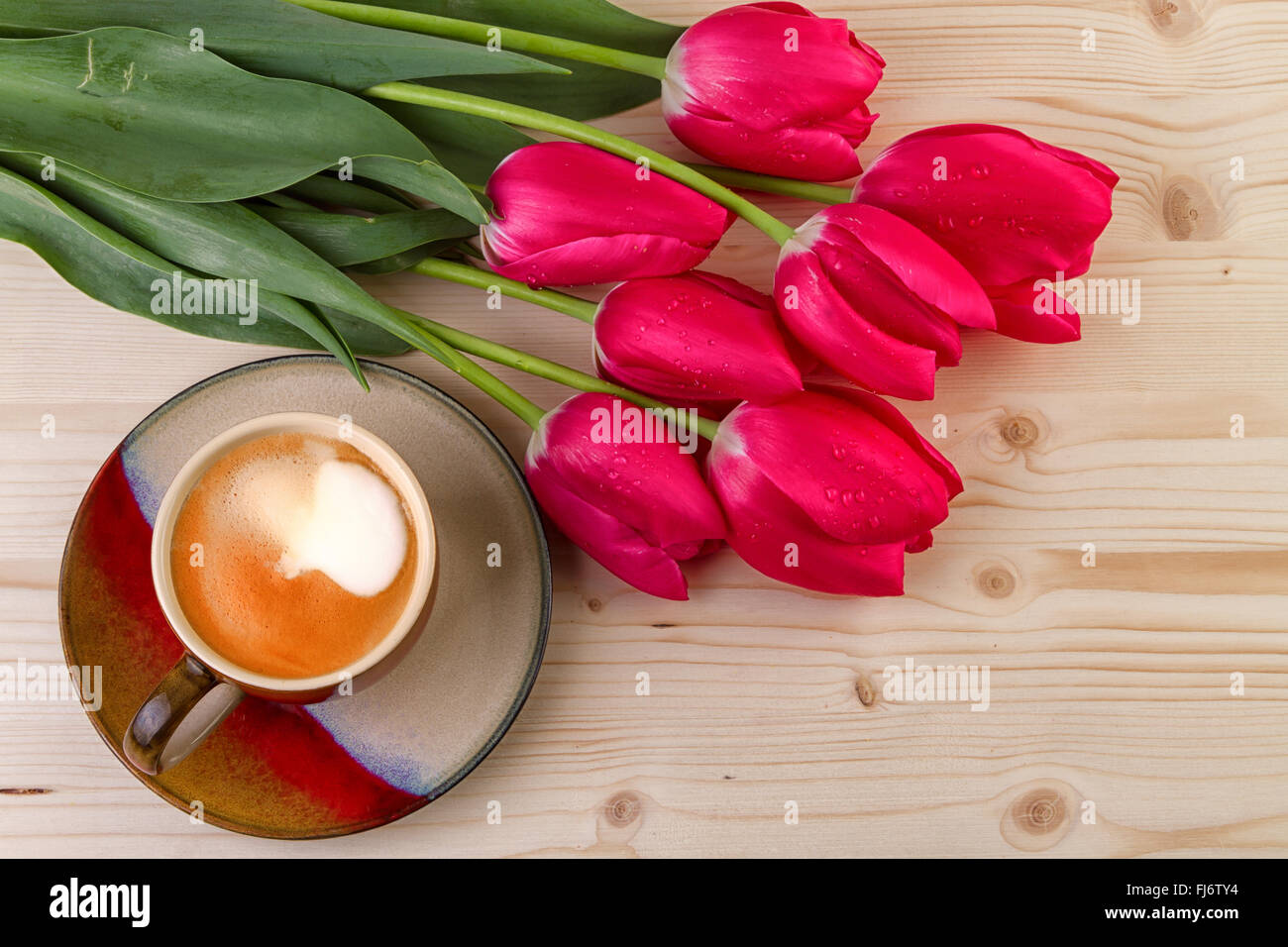 Tasse de café avec des tulipes rouges sur fond de bois Banque D'Images