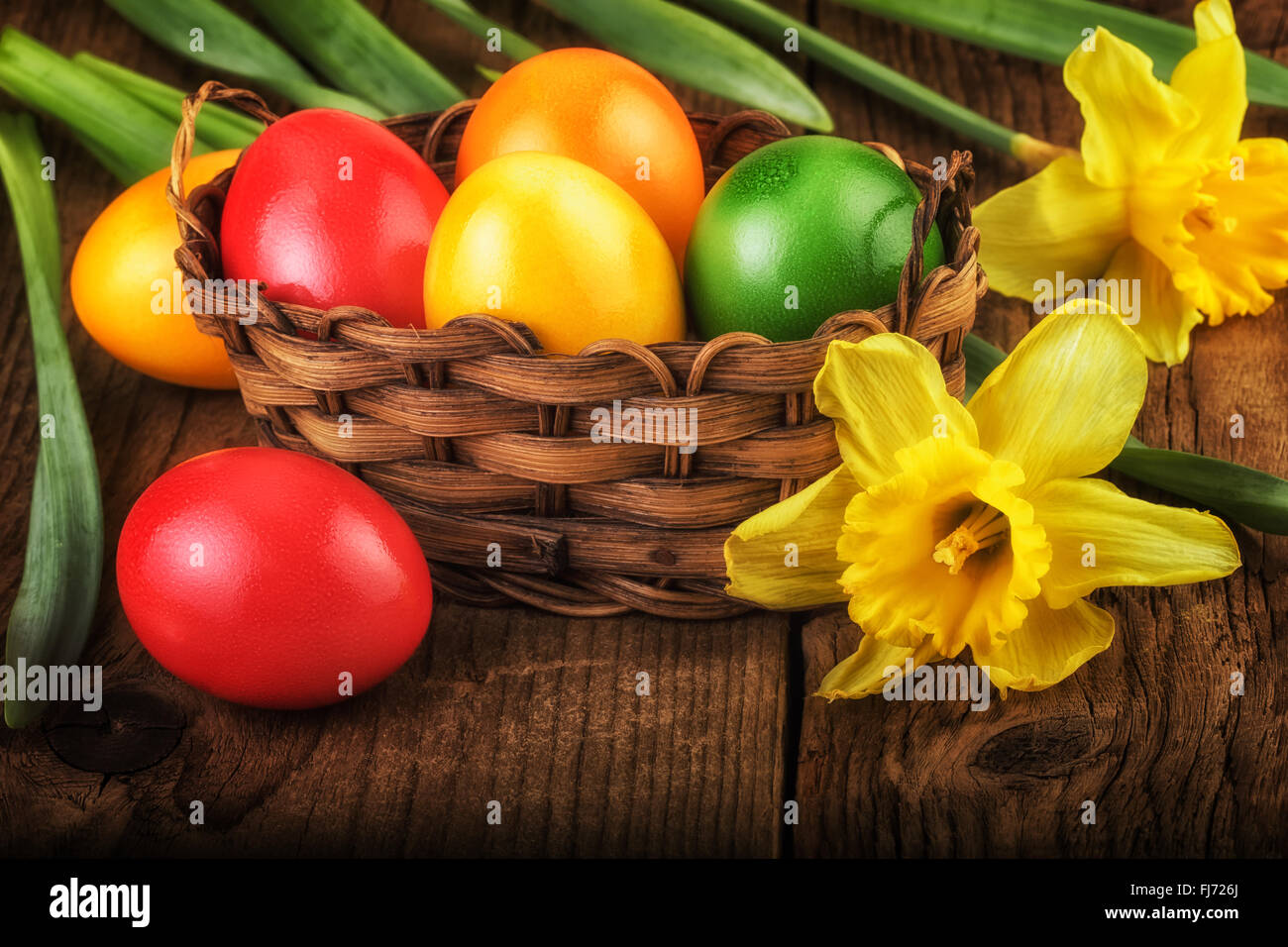 Les oeufs de Pâques colorés dans panier sur fond de bois foncé Banque D'Images