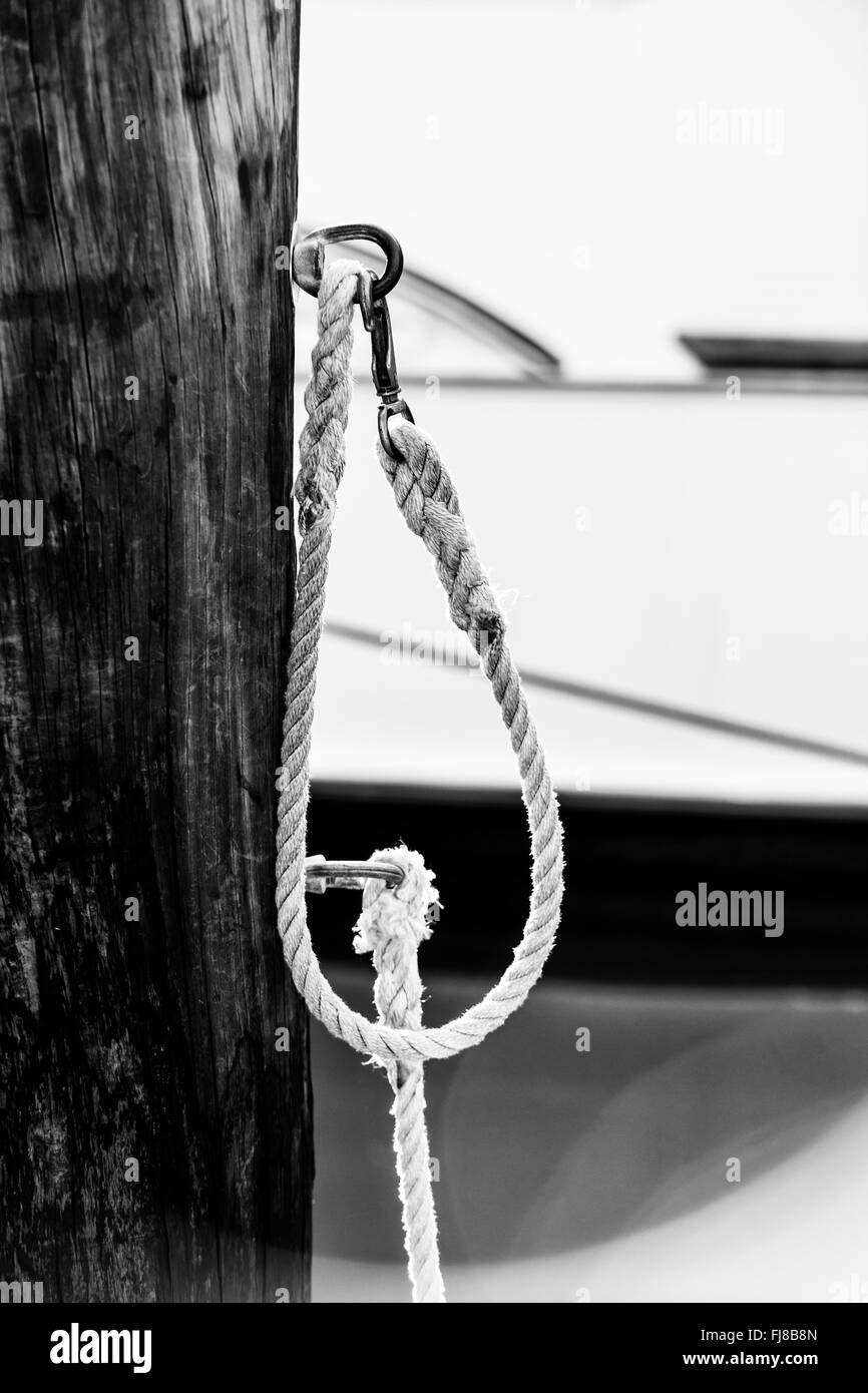 Fragment de corde nautique avec clôture en bois patiné dans le port de Key West en Floride, bateaux ancrés en arrière-plan.noir un Banque D'Images