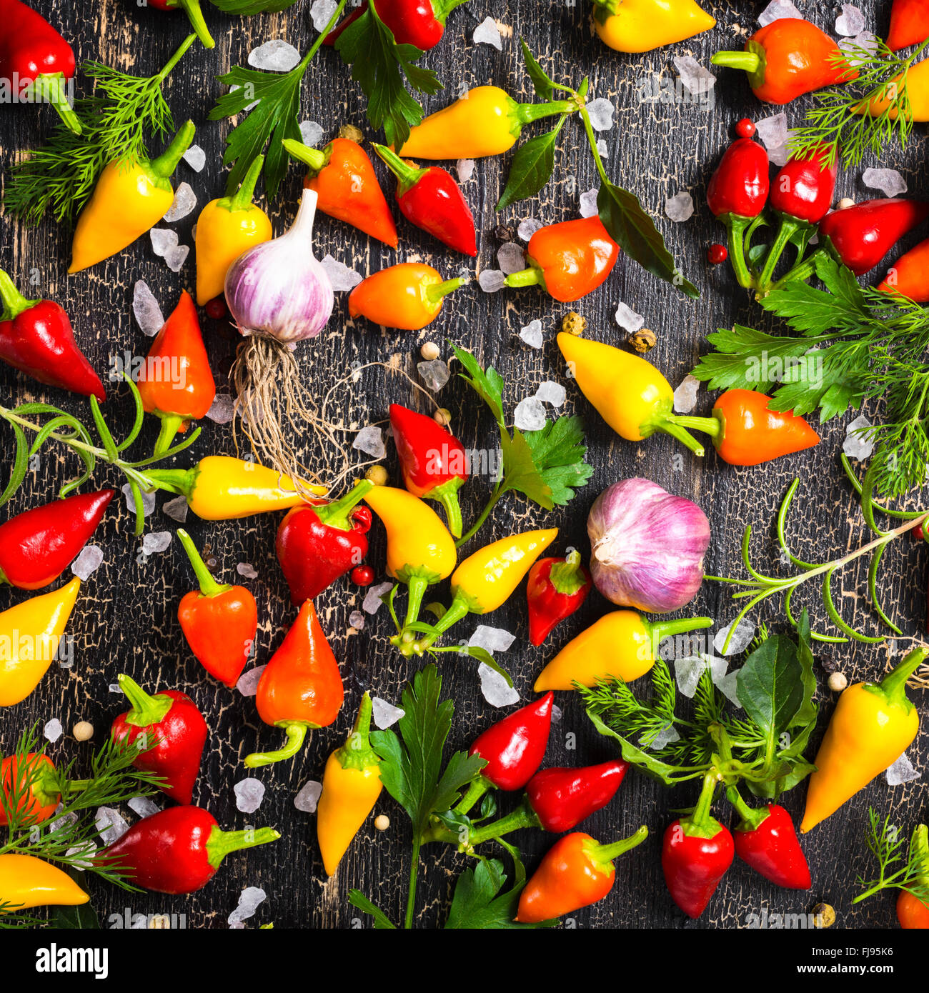 Vue de dessus de jaune à maturité, Red Hot Chili Peppers, sel de mer, verdure différents, les poivrons et l'ail noir sur noir fissures backgroun Banque D'Images