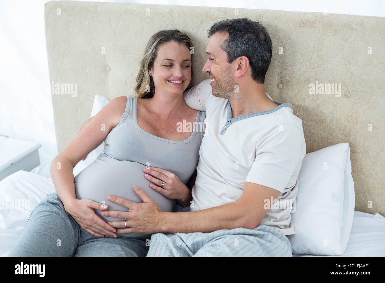 Expecting couple lying on bed and chatting Banque D'Images