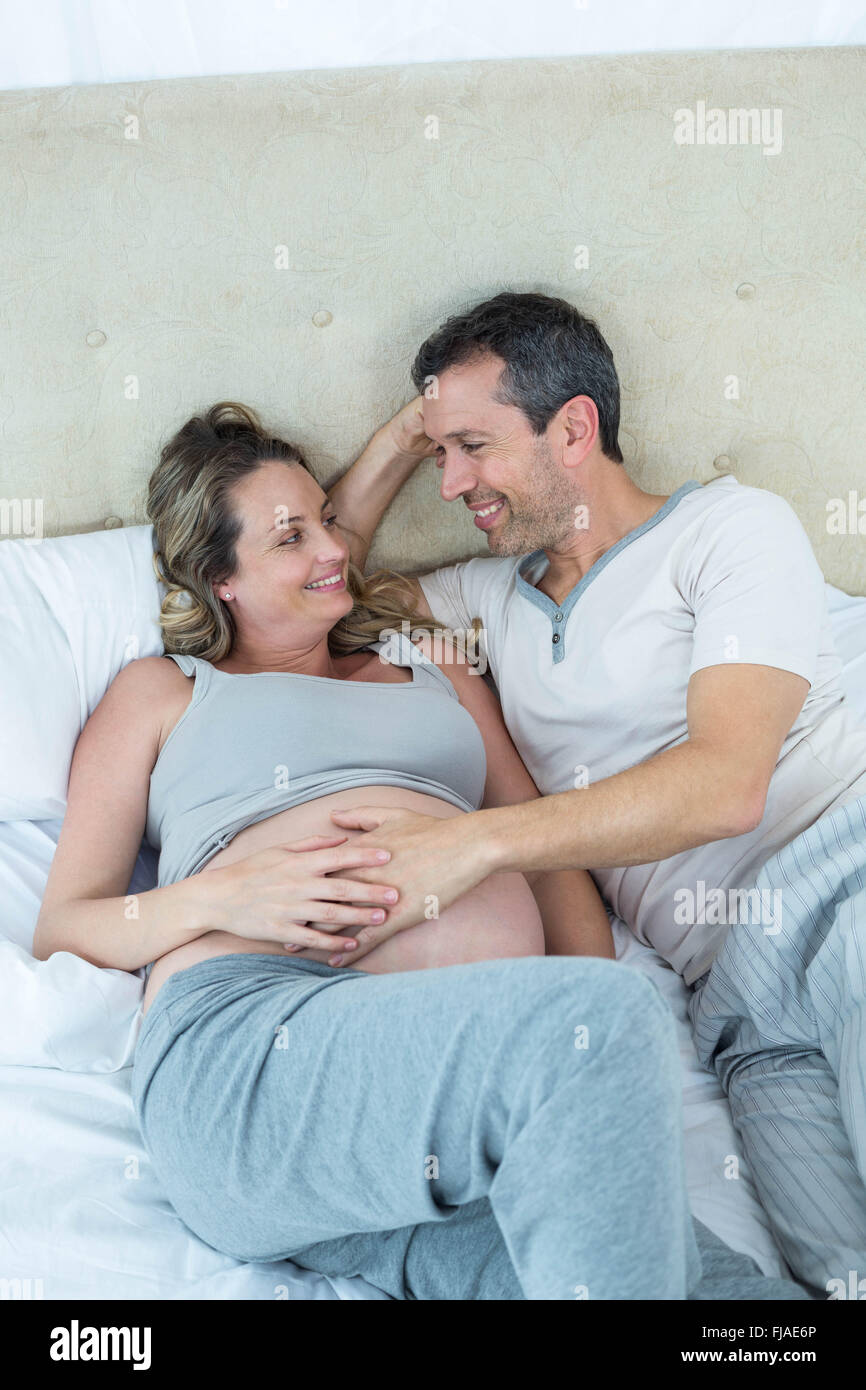 Expecting couple lying on bed and chatting Banque D'Images