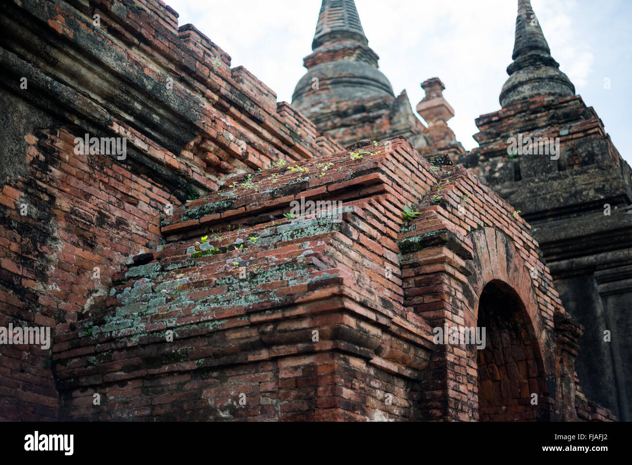 Détail du stuc du temple d'Abeyadana Bagan Myanmar // BAGAN, Myanmar — L'extérieur en briques rouges altérées du temple d'Abeyadana présente des vestiges de sa décoration originale en stuc ornée. Datant de la fin du XIe siècle ou du début du XIIe siècle, le temple est situé près du temple Nagayon dans la zone archéologique de Bagan et est associé dans la légende à la reine Abeyadana, bien qu'aucune preuve solide ne confirme ce lien. Les briques du temple étaient à l'origine recouvertes de stuc richement décoré, avec des taches de ce revêtement résistant à base de chaux encore visibles sur la surface altérée. Le stuc de Bagan était typiquement un salut Banque D'Images