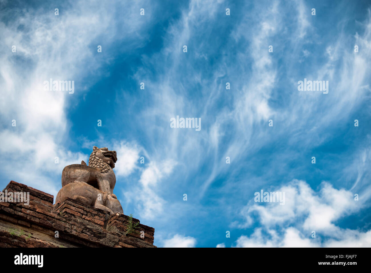 Statue du lion gardien du temple d'Abeyadana Bagan Myanmar // BAGAN, Myanmar — Une statue de lion gardien restaurée placée au sommet d'un éléphant orne le toit du temple d'Abeyadana (également connu sous le nom APE-Ya-da-na ou APE-Yadana-Phaya). Le temple date de la fin du XIe siècle ou du début du XIIe siècle et est situé près du temple Nagayon, juste au sud du village de Myinkaba dans la zone archéologique de Bagan. Le temple Abeyadana se distingue parmi les temples de l'ère païenne pour son imagerie bouddhiste Mahayana dans ses fresques, contrastant avec les thèmes Theravada plus communément trouvés dans d'autres temples de l'époque. Le temple présente SLO Banque D'Images