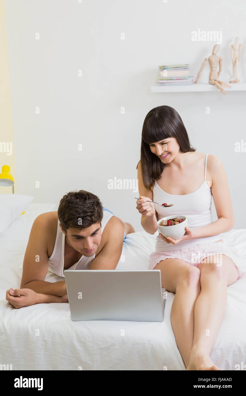Jeune couple looking at laptop on bed Banque D'Images