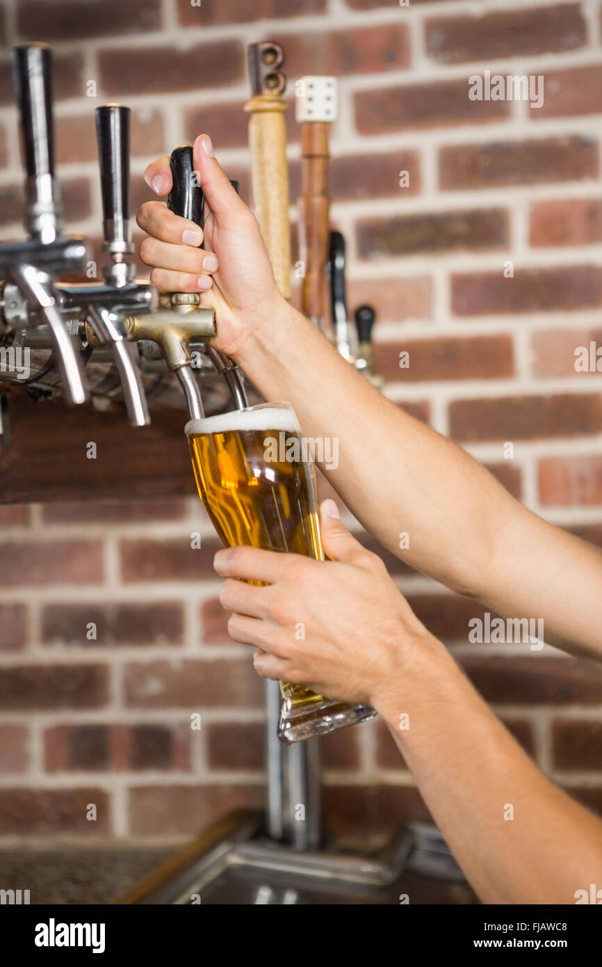 Barman beau versant une pinte de bière Banque D'Images