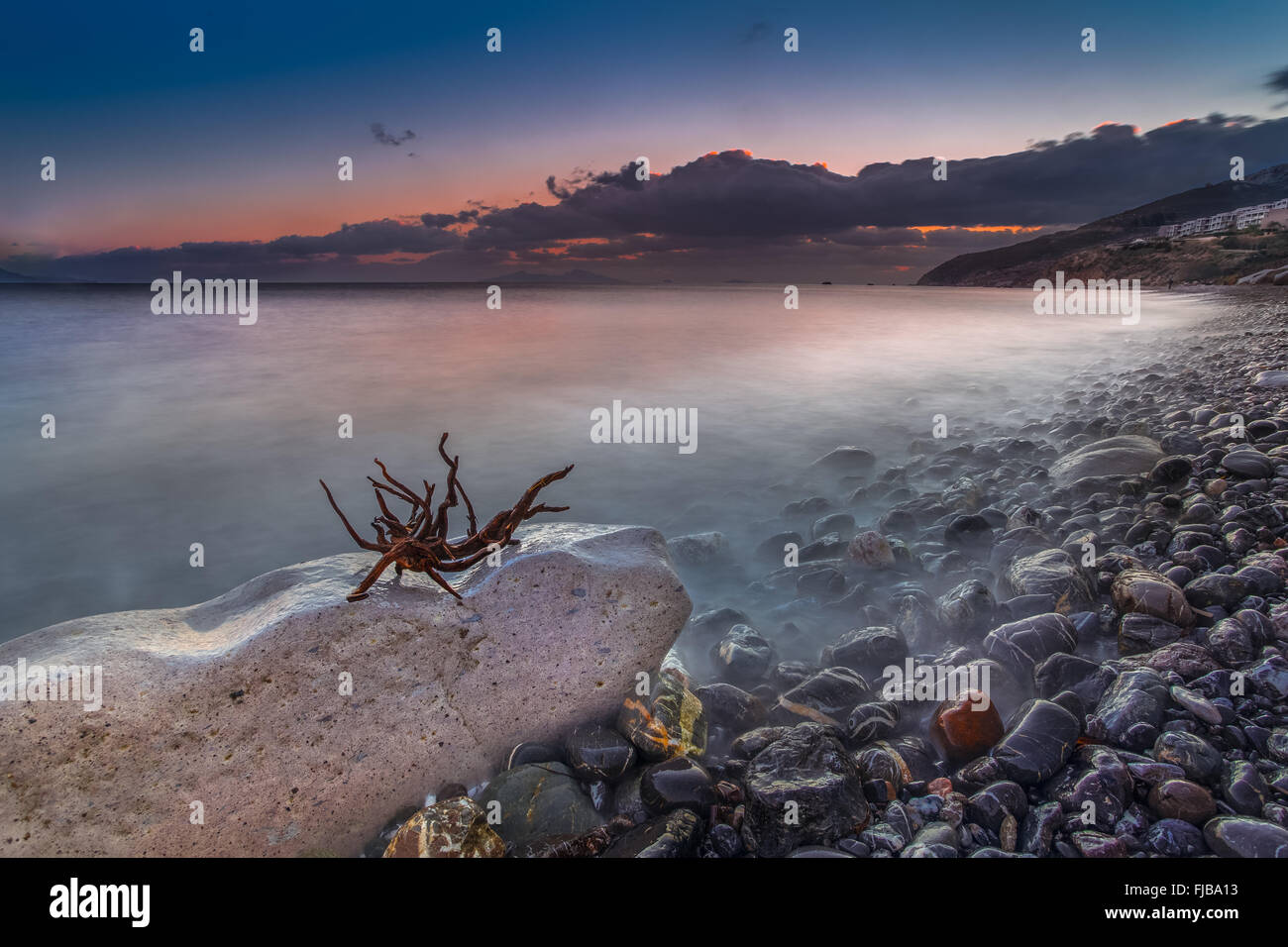 Long exposé sur la mer d'une plage de galets de l'île de Kos Grèce pendant le coucher du soleil. Banque D'Images