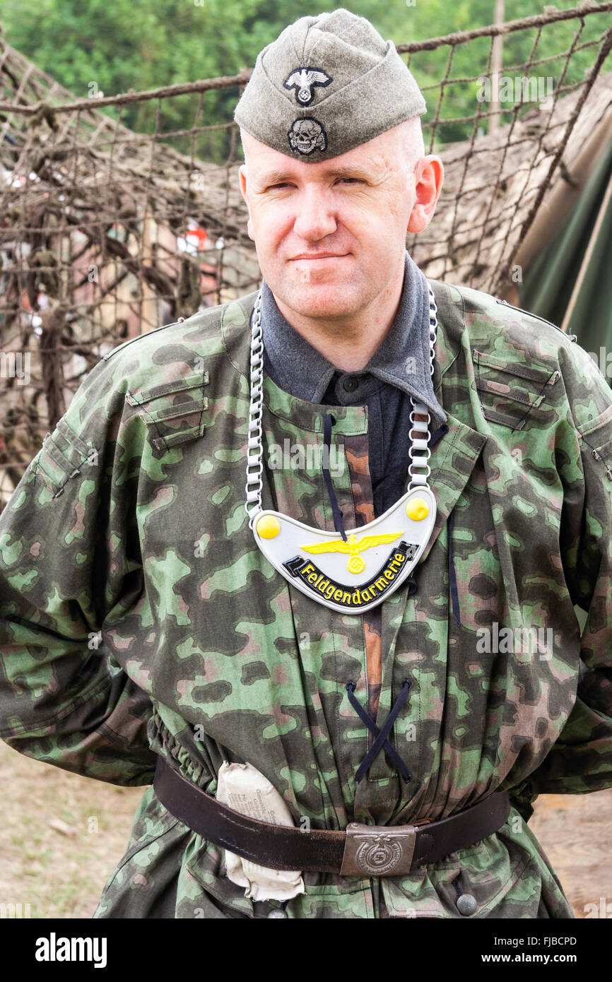 La guerre et la paix, l'Angleterre. WW2 re-enactment. L'homme de la police militaire allemande, le Feldgendarmerie, souriant à la visionneuse à permanent. Le port de gorgerin. Banque D'Images