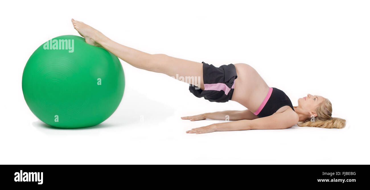 Femme enceinte en utilisant le yoga ball l'exécution de l'exercice lever la hanche. Banque D'Images