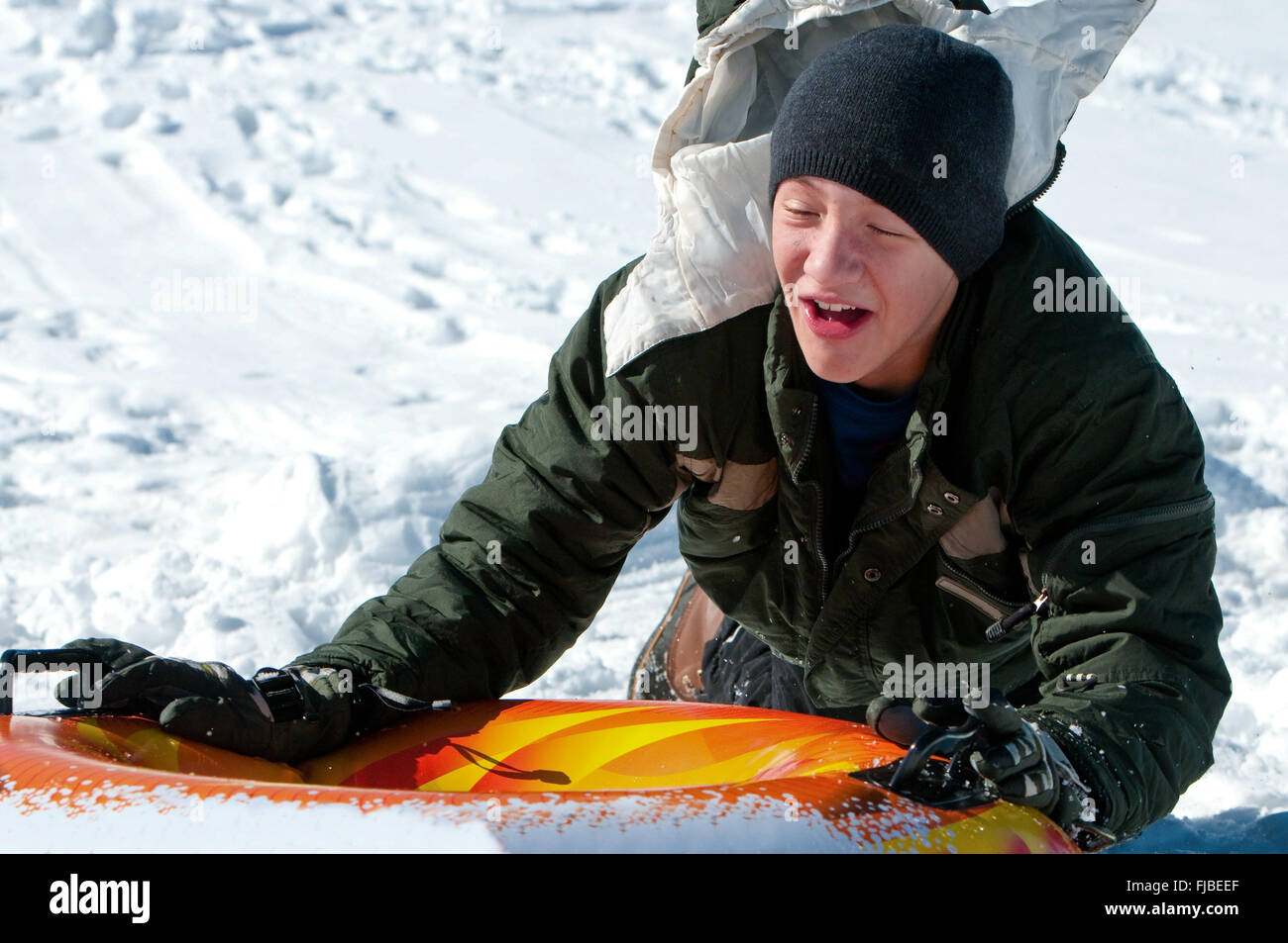 Cute adolescent dans la descente de toboggan d'un tube sur une colline de neige en riant. Banque D'Images