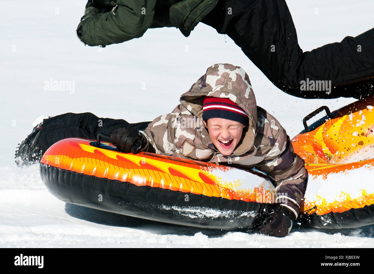 Jeune garçon sur un snow tube rire et s'amuser en vacances Banque D'Images