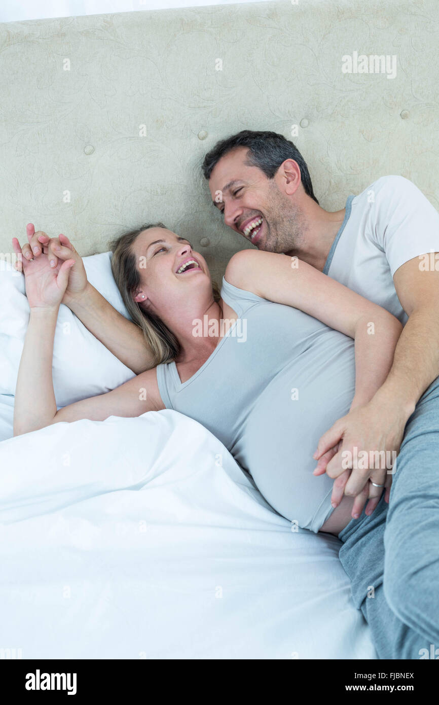 Expecting couple lying on bed and chatting Banque D'Images