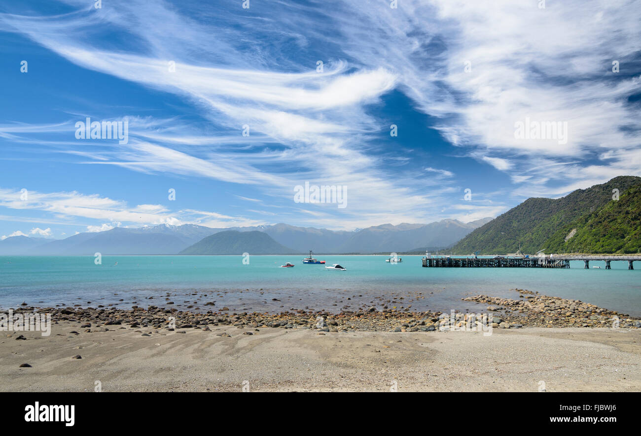 Bateau de pêche au quai et la mer turquoise, ciel nuageux, Jackson Bay, côte ouest, Tasman, ile sud Nouvelle Zelande Banque D'Images