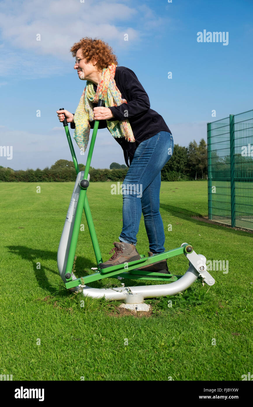Femme exerçant sur la marche de la machine dans un parc public Banque D'Images