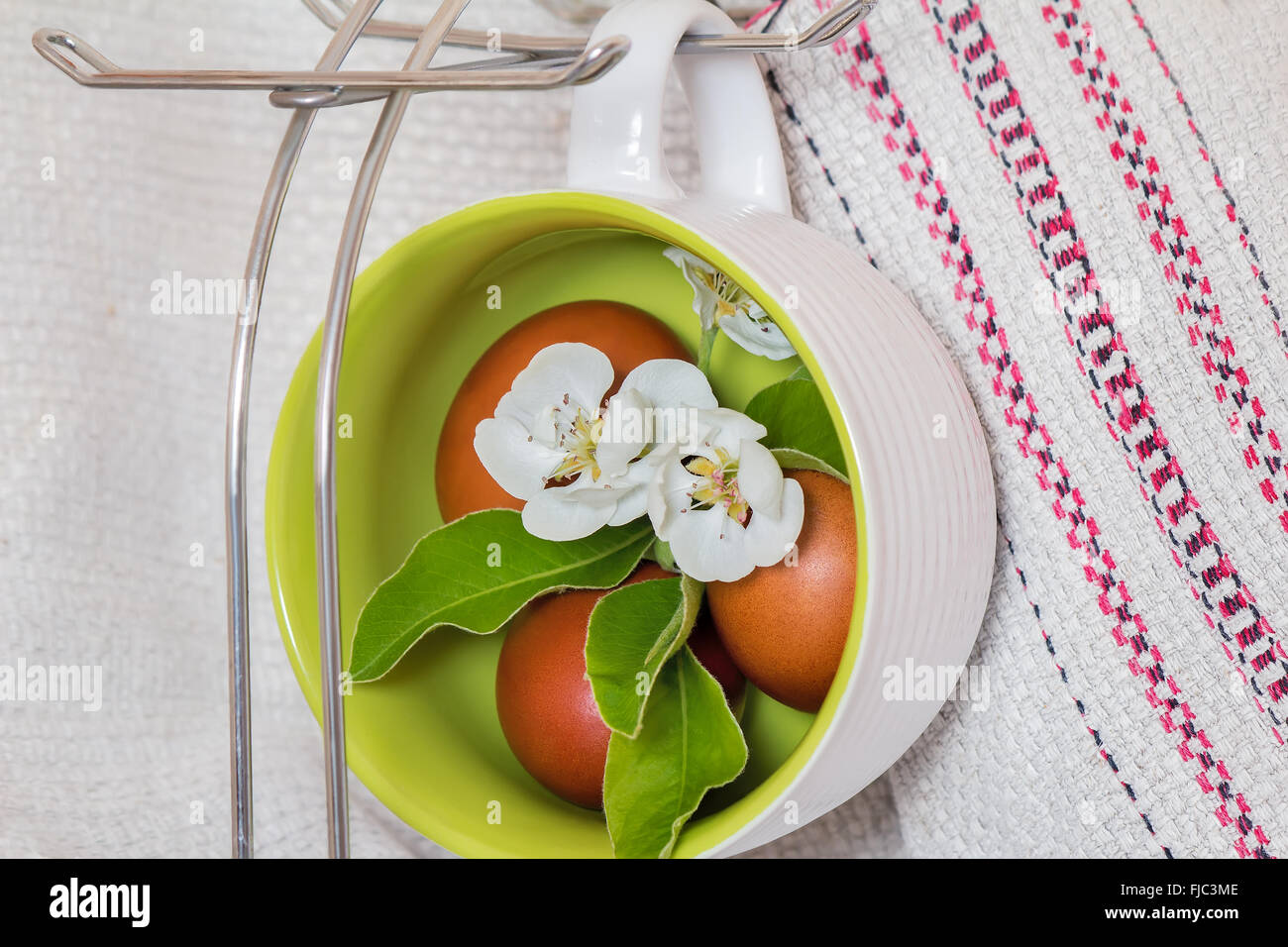 Les teintes en rouge et des oeufs de Pâques Apple Blossoms sont installés dans de grandes tasses en céramique. Banque D'Images