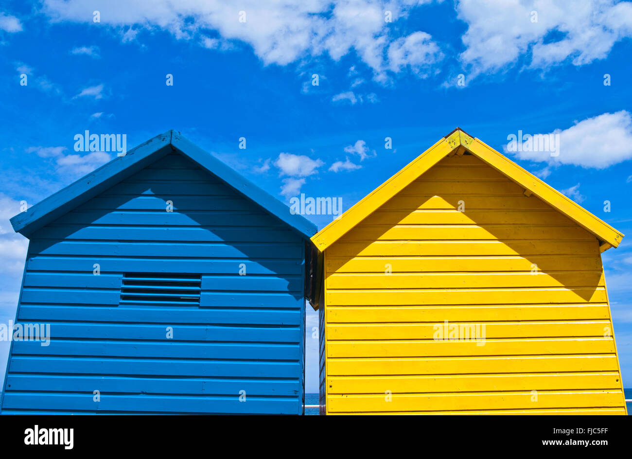 Deux couleurs bleu et jaune de cabanes de plage vu contre un ciel bleu profond, l'été, Whitby, North Yorkshire, England, UK Banque D'Images