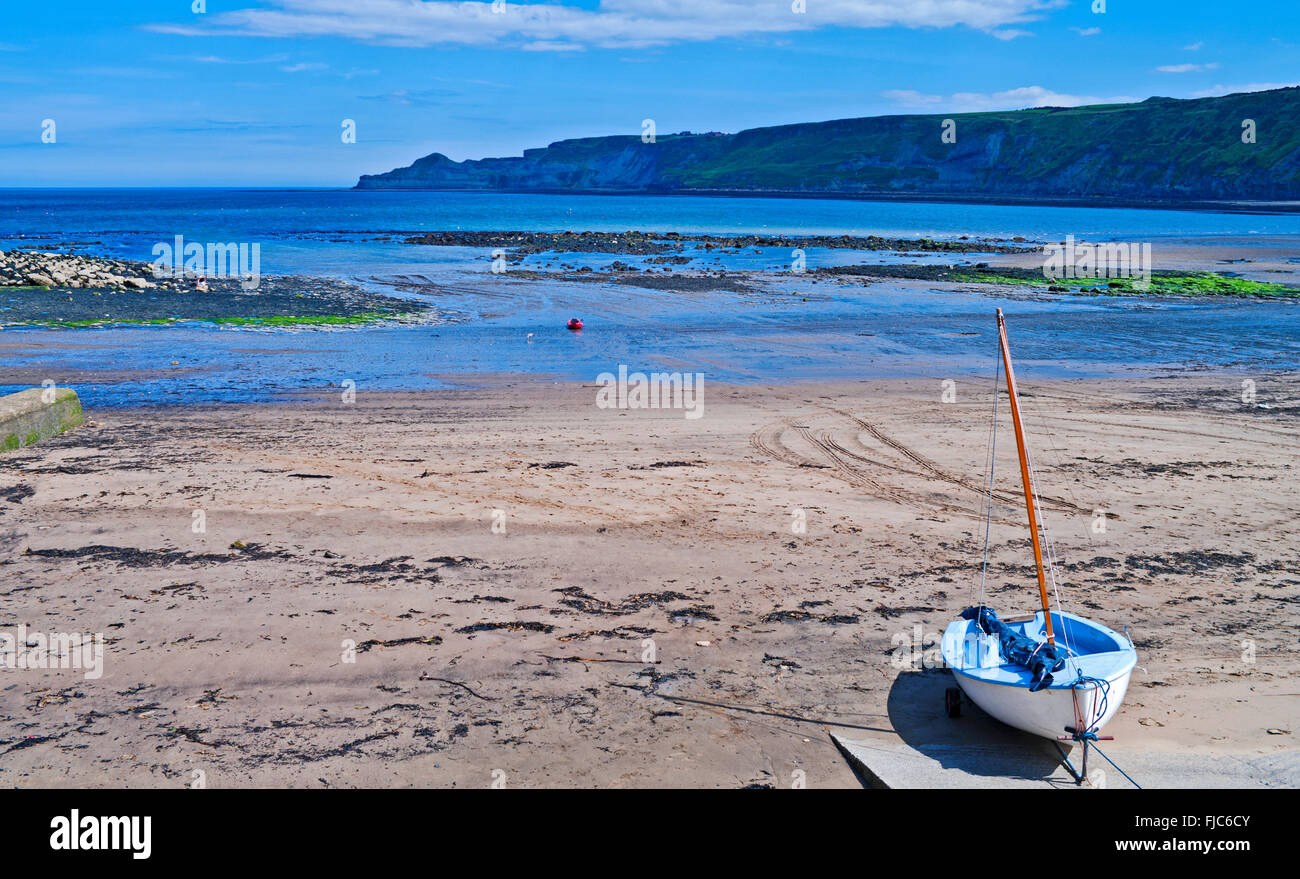 La voile canot amarré à la fin de halage, sur la plage de sable à Runswick Bay, North Yorkshire, Angleterre Royaume-uni Littoral du patrimoine, de l'été. Banque D'Images