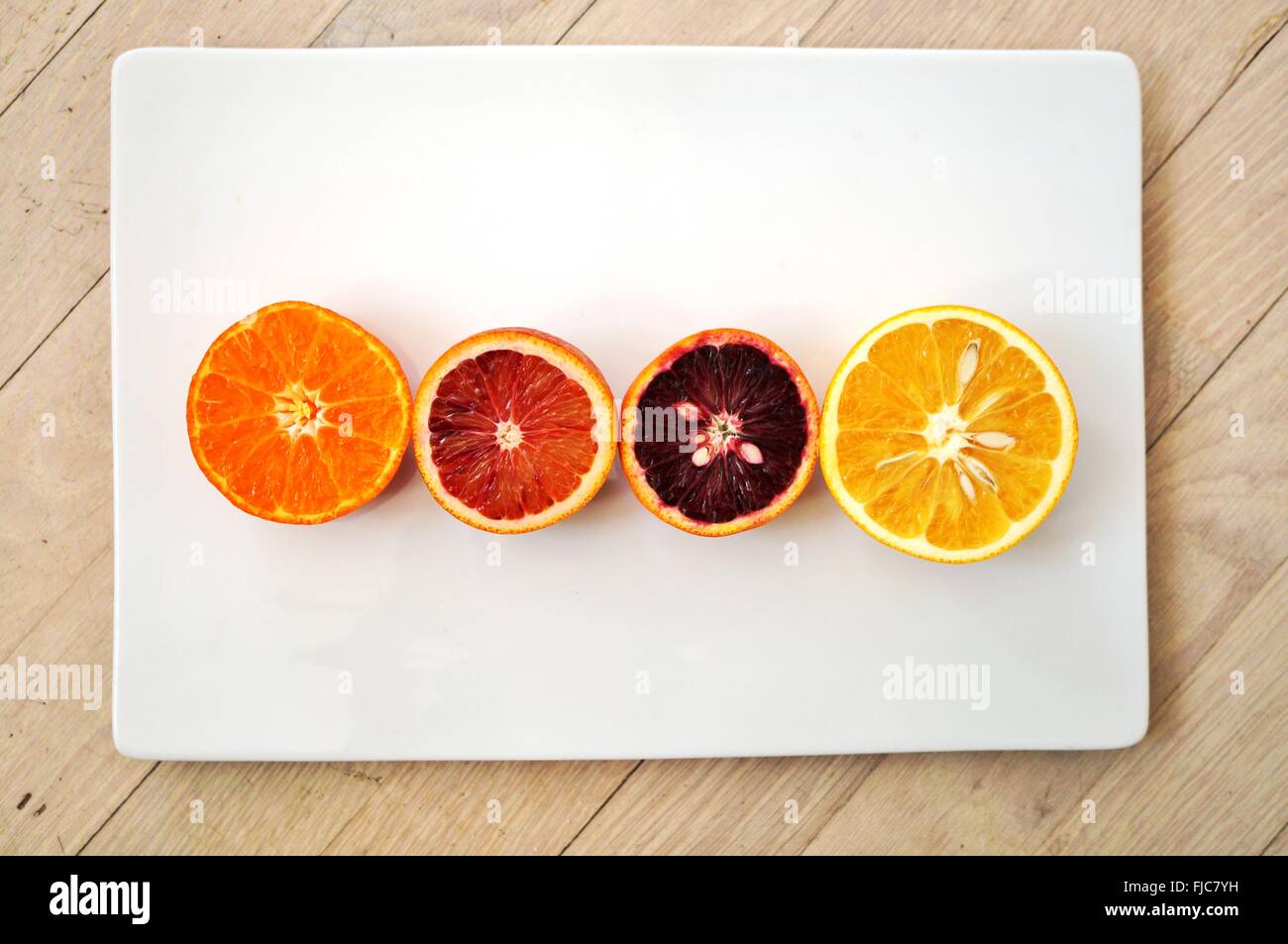 Sang rouge rubis, les oranges, clémentines et oranges navel réduit de moitié sur une assiette blanche Banque D'Images