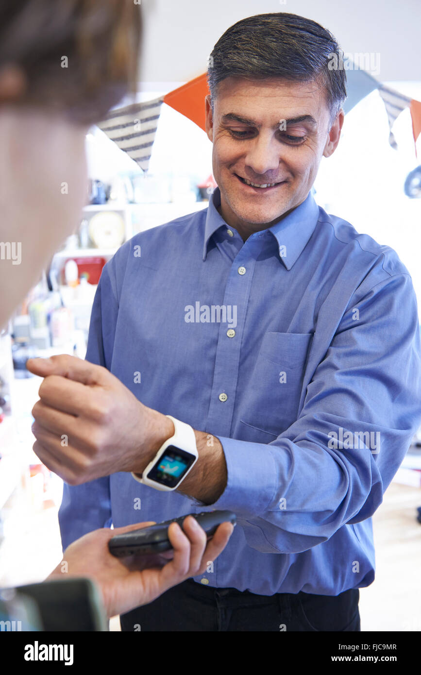 L'homme à l'aide de l'application de paiement sans contact sur Smart Watch In Store Banque D'Images