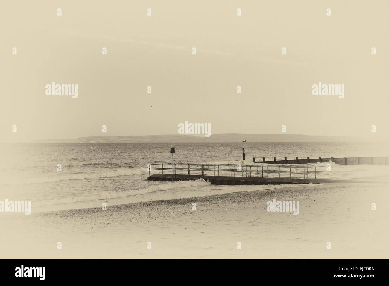 Une photo en noir et blanc d'un coucher du soleil la lumière d'un oiseau volant dans le ciel à la mer, à la recherche d'un quai, prise à la plage avec san Banque D'Images