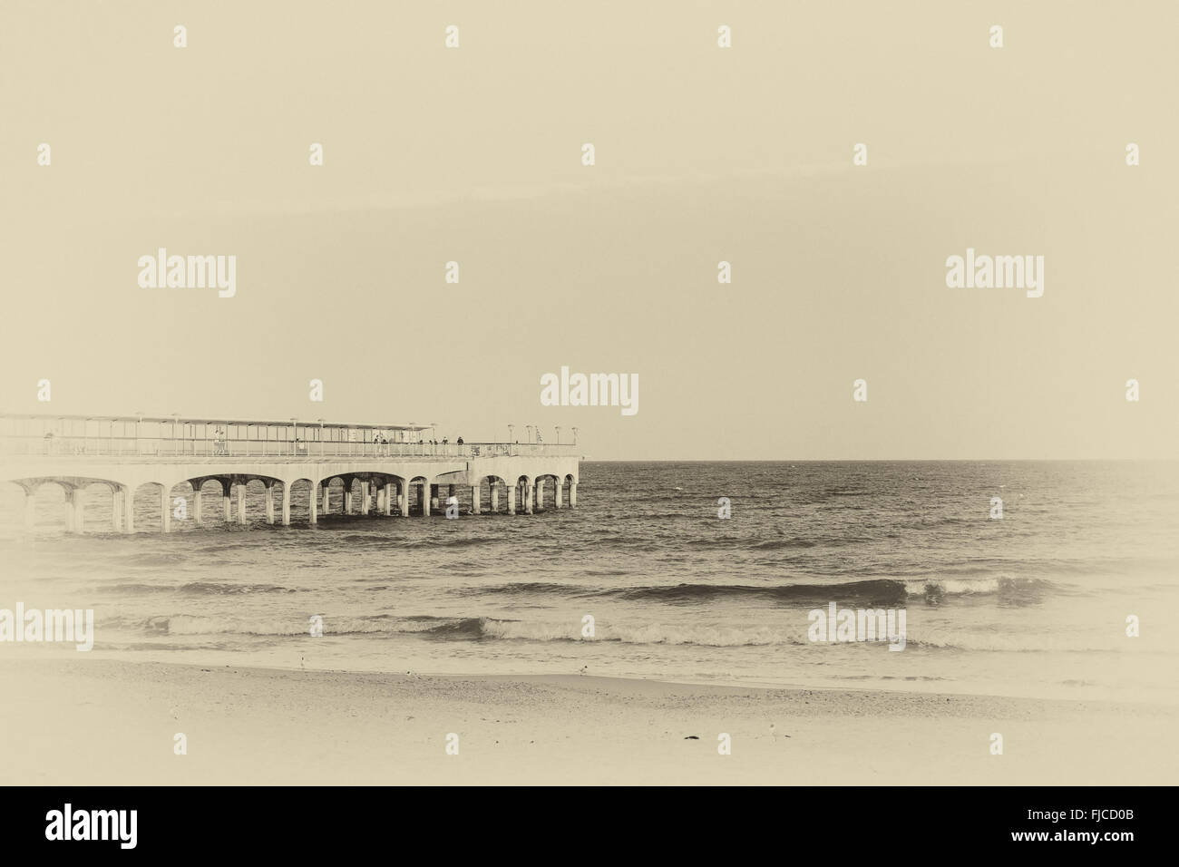 Une photo en noir et blanc d'un coucher du soleil à la lumière, à un quai, prise à la plage avec du sable et pas de nuages dans le ciel de l'Europe le Banque D'Images