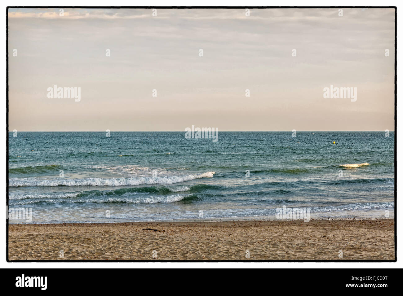 Une image couleur d'un coucher du soleil doré de la lumière avec la teinte rose, en regardant les vagues, sur la plage de sable et d'un pas de nuages dans le sk Banque D'Images