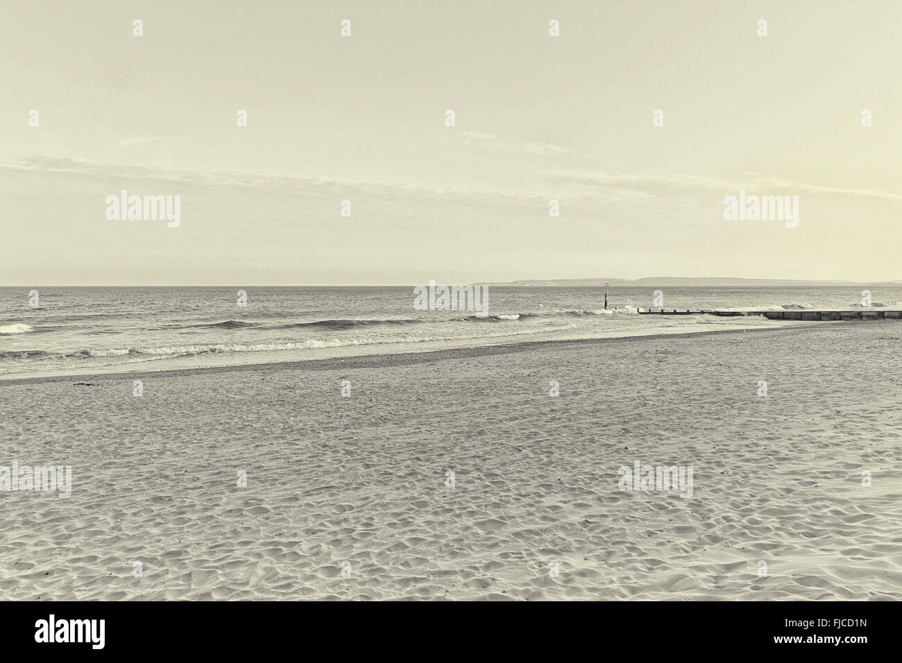 Une image en noir et blanc de lumière au coucher du soleil, d'un pilier à la direction de la mer à la plage de sable et une bande de clo spectaculaire Banque D'Images