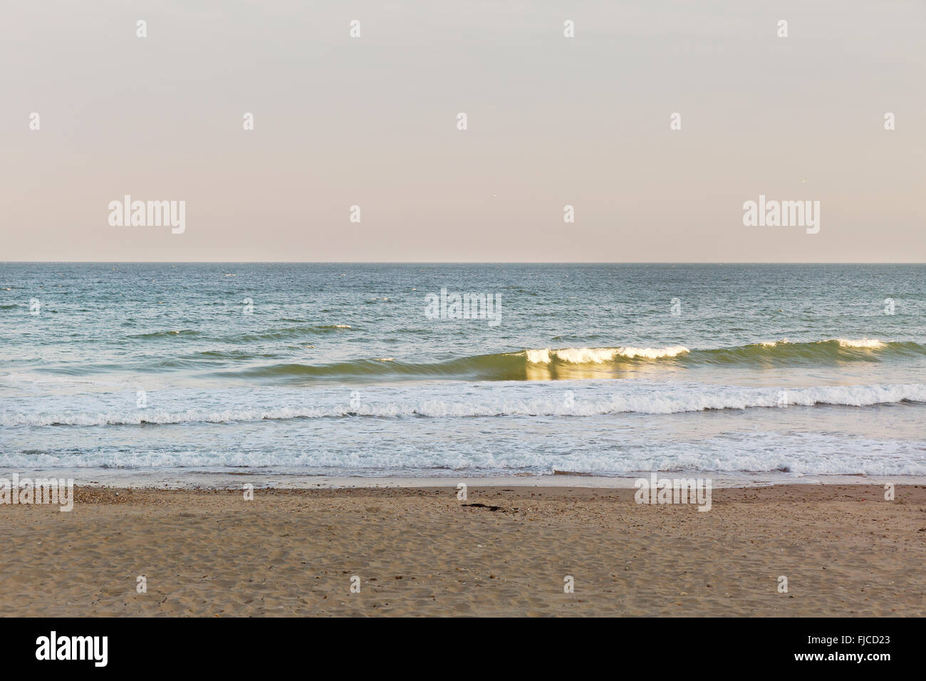 Golden sunset light d'une silhouette d'un surfeur sur sa planche vers la mer à la plage de sable et pas de nuages dans le Banque D'Images