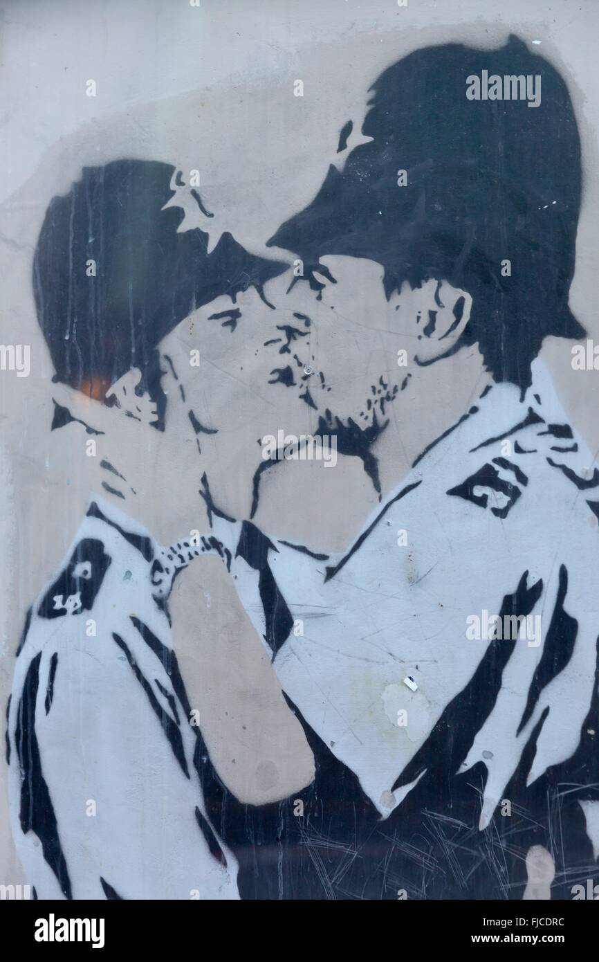 Un graffiti de Banksy, Bristol, artiste de la police deux hommes s'embrasser sur un mur d'une maison en brique Banque D'Images