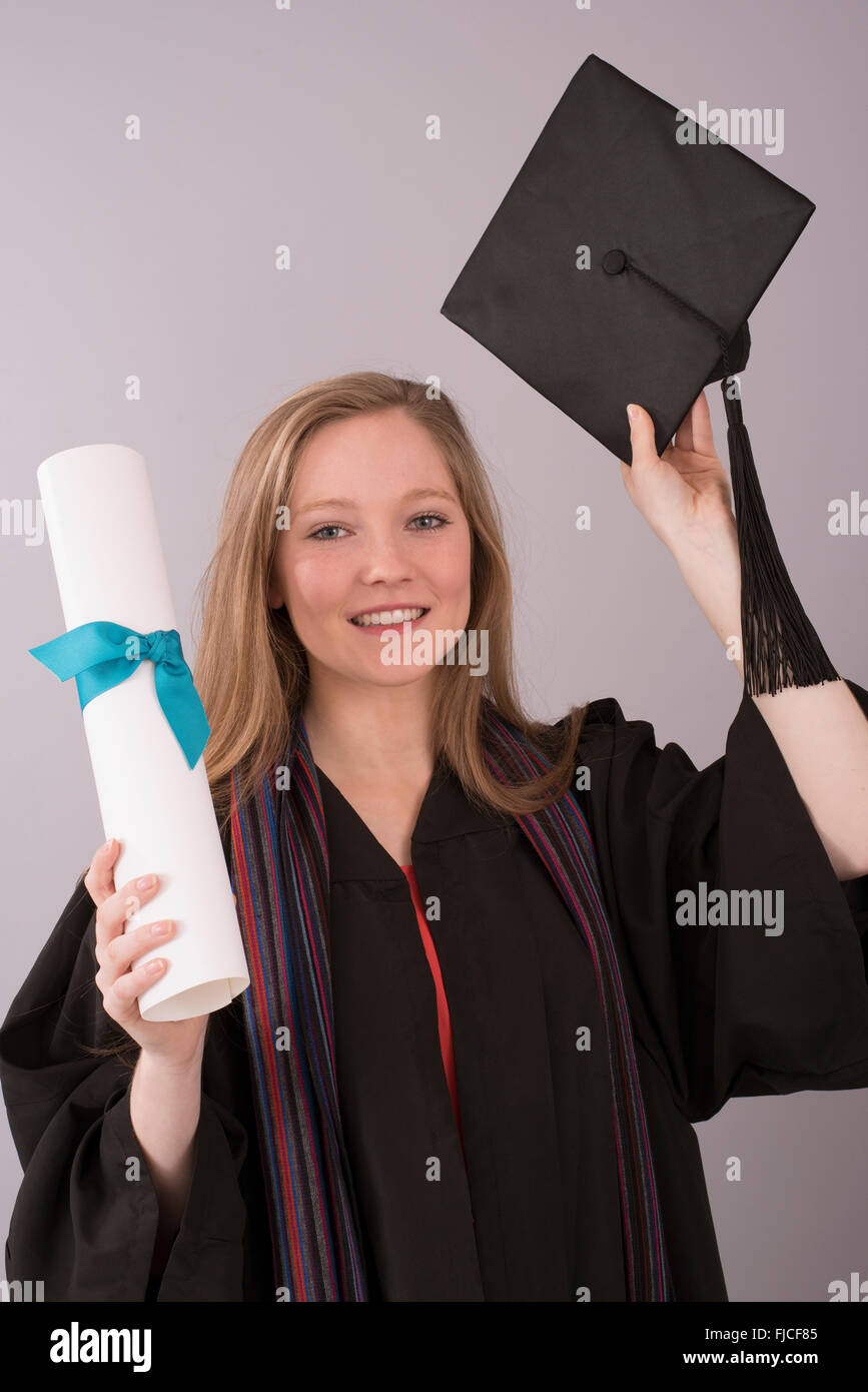 Jeune diplômé en cap and gown avec diplôme Banque D'Images