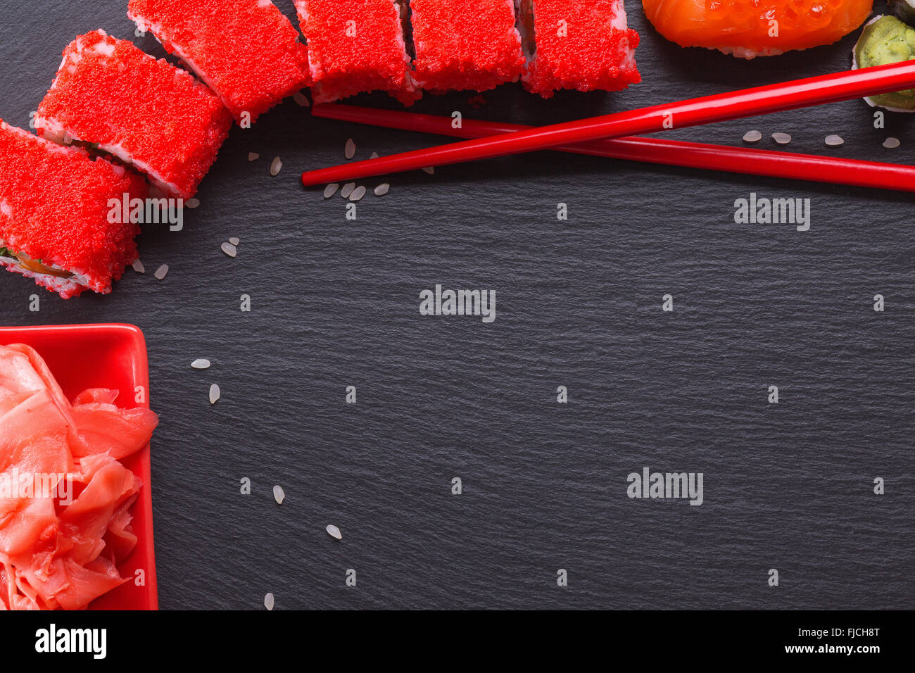 Rouleaux de sushi avec des baguettes rouge sur un tableau d'ardoise. Banque D'Images