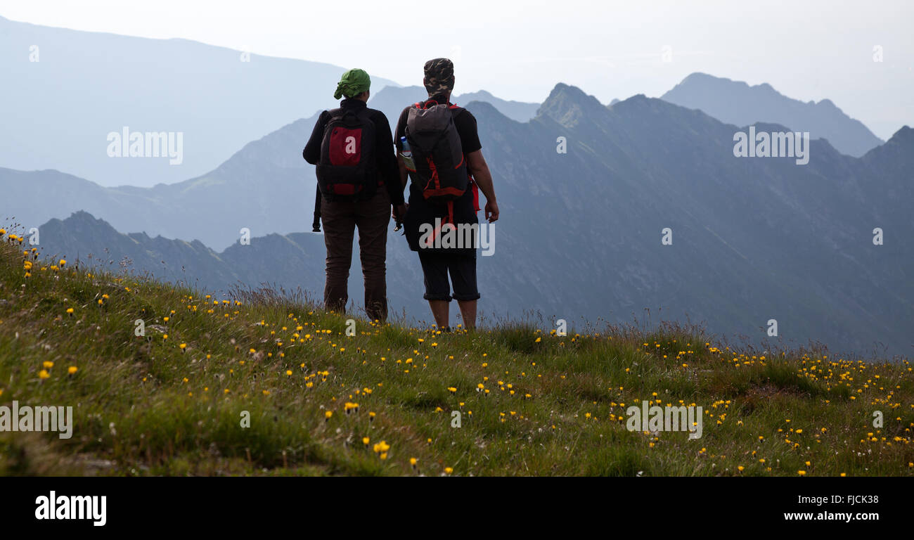 Les randonneurs de couple admiring view et prendre des photos de hautes montagnes Banque D'Images