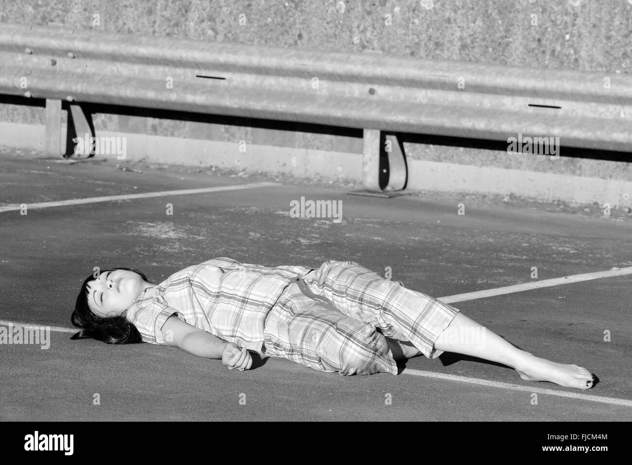 Juillet 2015 - young woman playing morte dans son pyjama sur le dessus d'un parking à plusieurs étages Banque D'Images