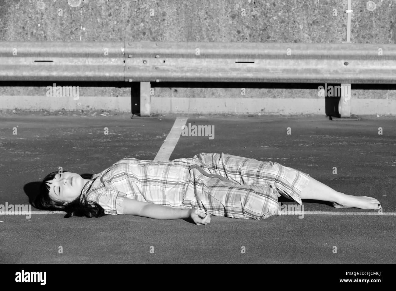 Juillet 2015 - young woman playing morte dans son pyjama sur le dessus d'un parking à plusieurs étages Banque D'Images