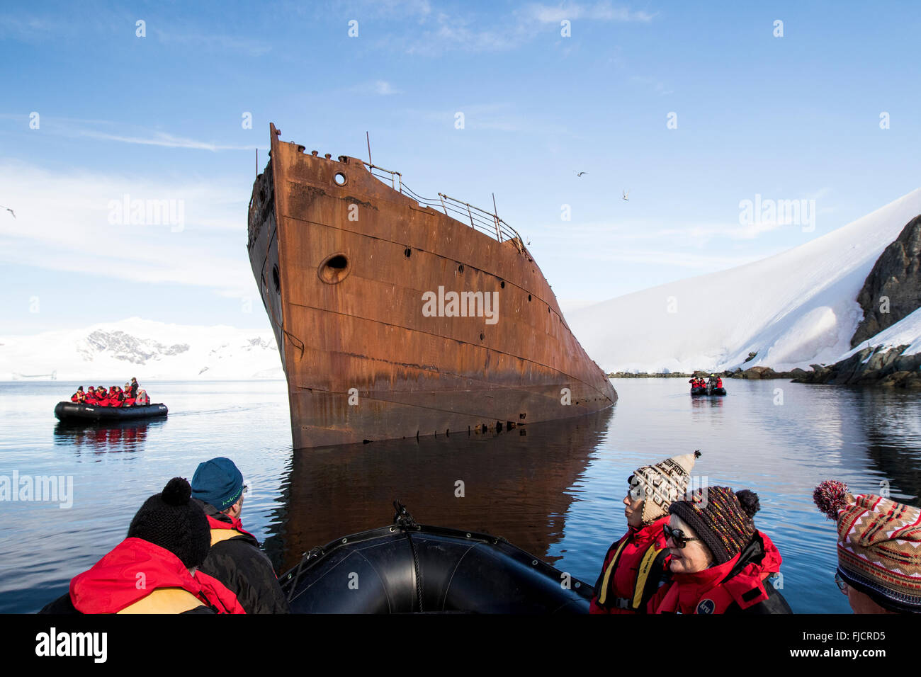 L'antarctique le tourisme avec les passagers des navires de croisière en zodiac et regardant de vieux baleinier historique. Banque D'Images