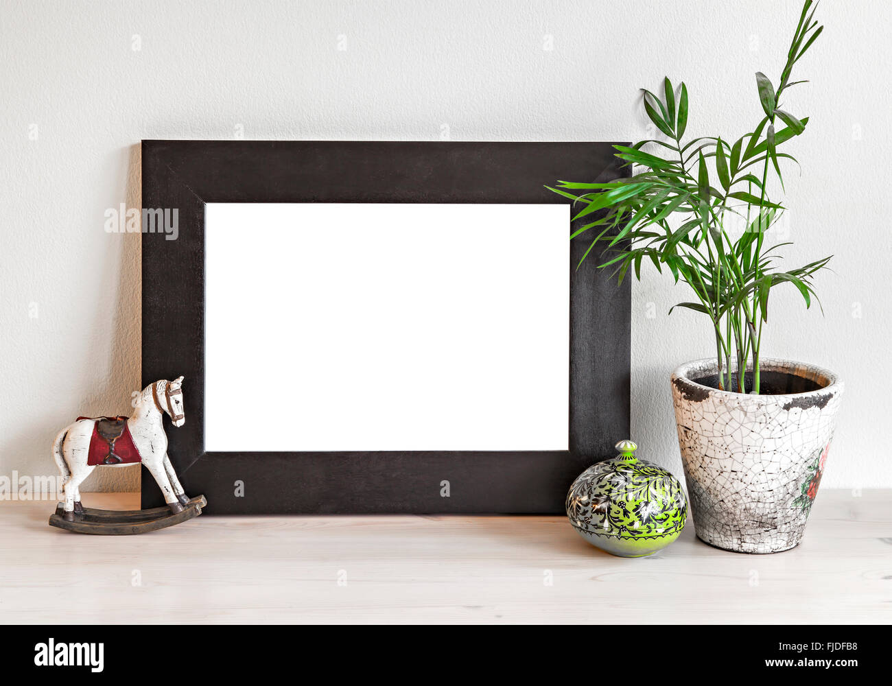 Image d'une maquette de scène avec cadre en bois, cheval jouet et plante en pot. Banque D'Images