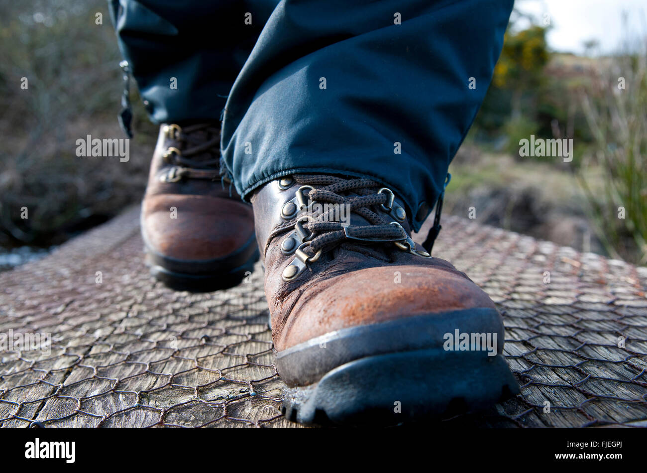 Close up, le niveau du sol, d'une personnes pieds portant des bottes de marche, faire un pas vers l'appareil photo. Banque D'Images