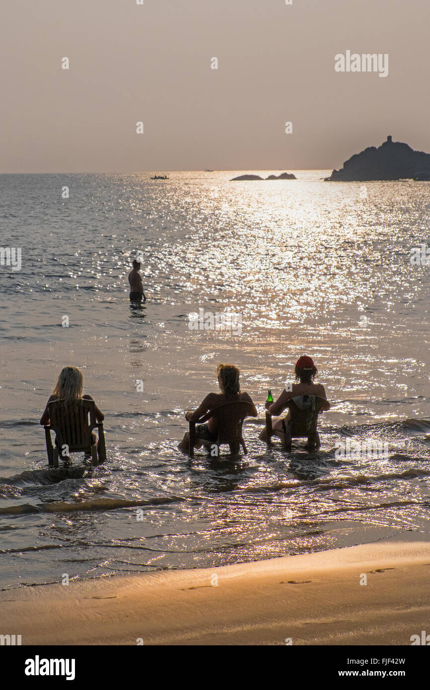 Backpackers d'avoir une bière au coucher du soleil sur Om Beach, Gokarna dans l'état indien du Karnataka Banque D'Images