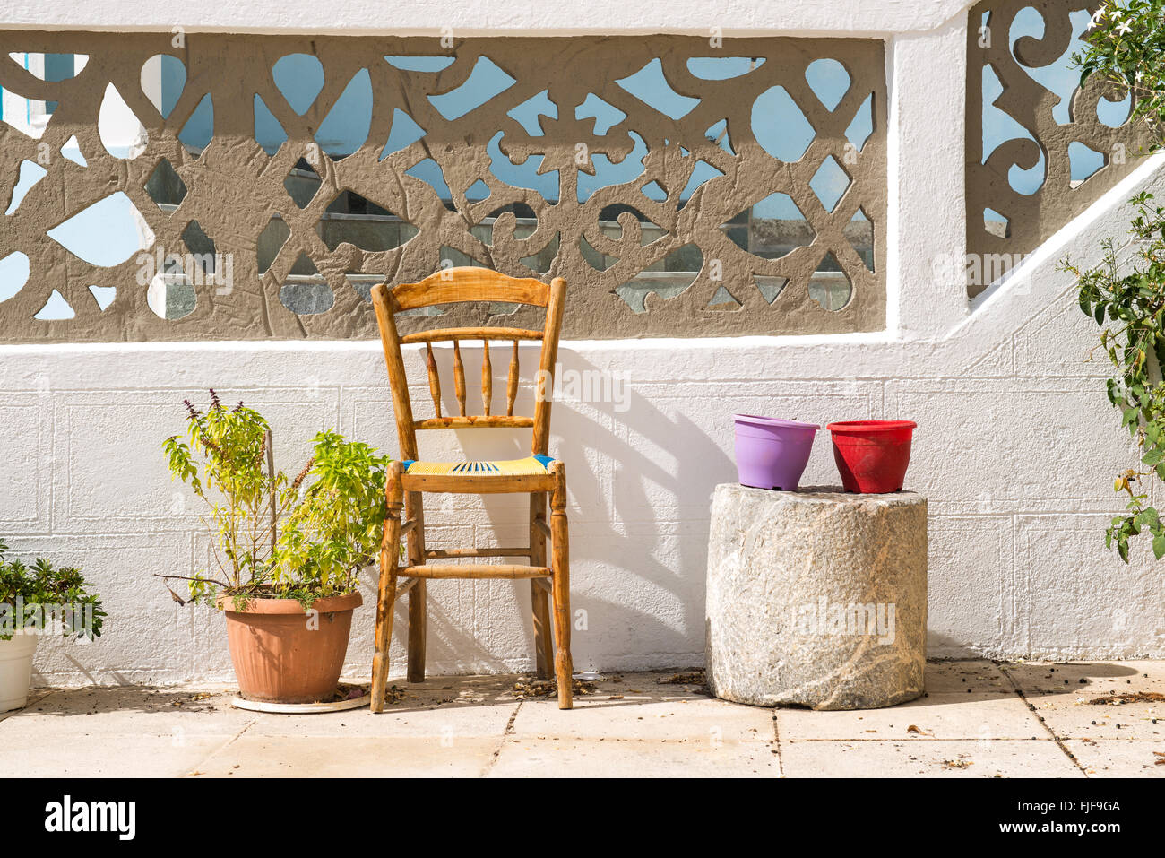 Pots de fleurs colorés et une chaise sur la rue de village traditionnel grec typique aux maisons blanches sur l'île de Karpathos, Grèce. Banque D'Images