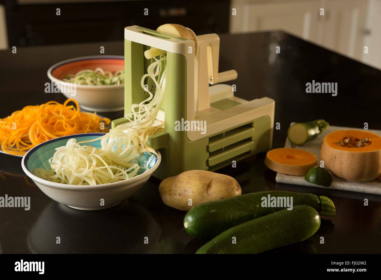Un spiralizer dans une cuisine domestique avec les courges, courgettes et pommes de terre les deux ensemble et spiralised ou nouilles ou renforts spiralés Banque D'Images