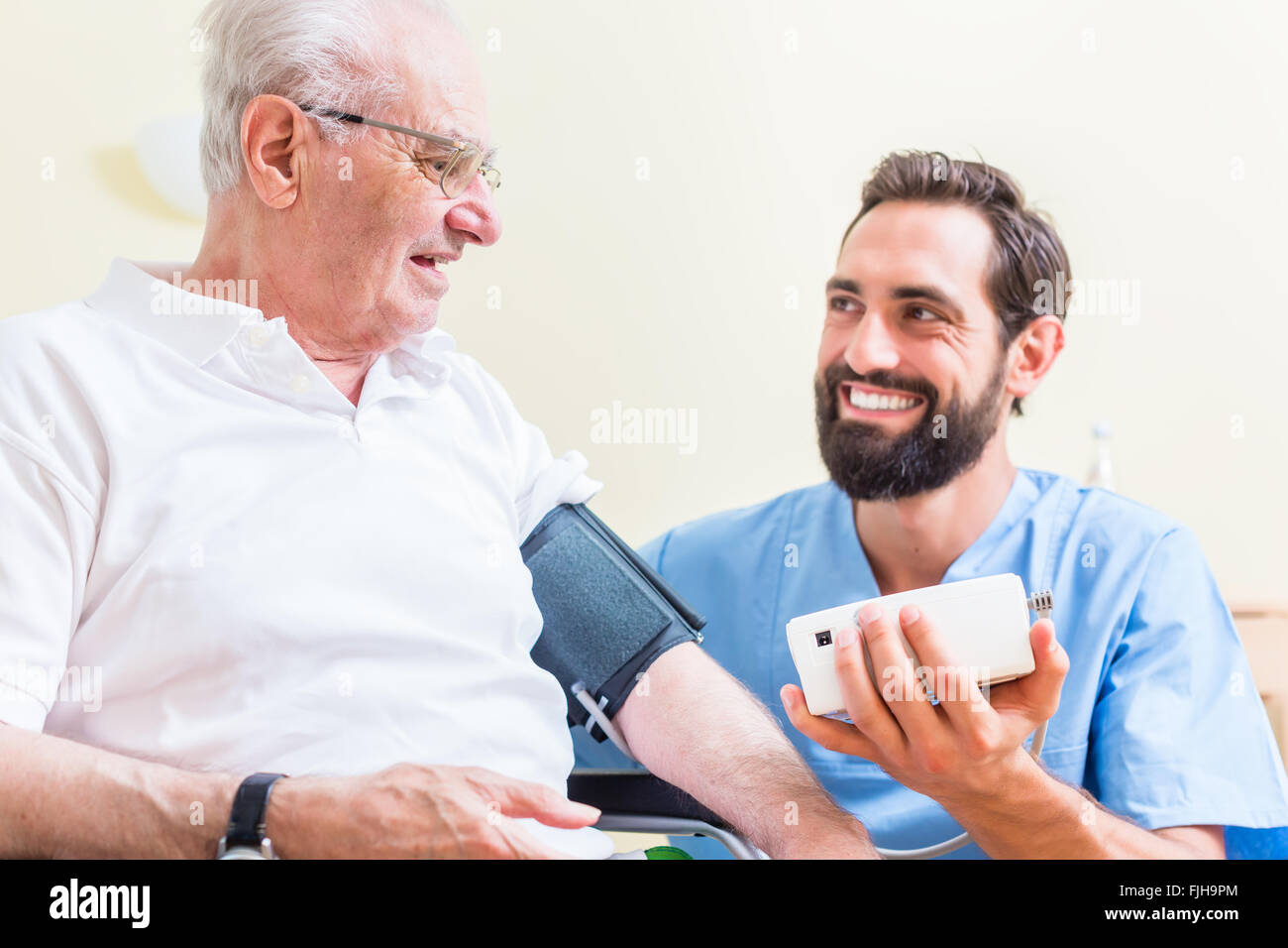 La mesure de la pression artérielle d'infirmière senior patient Banque D'Images