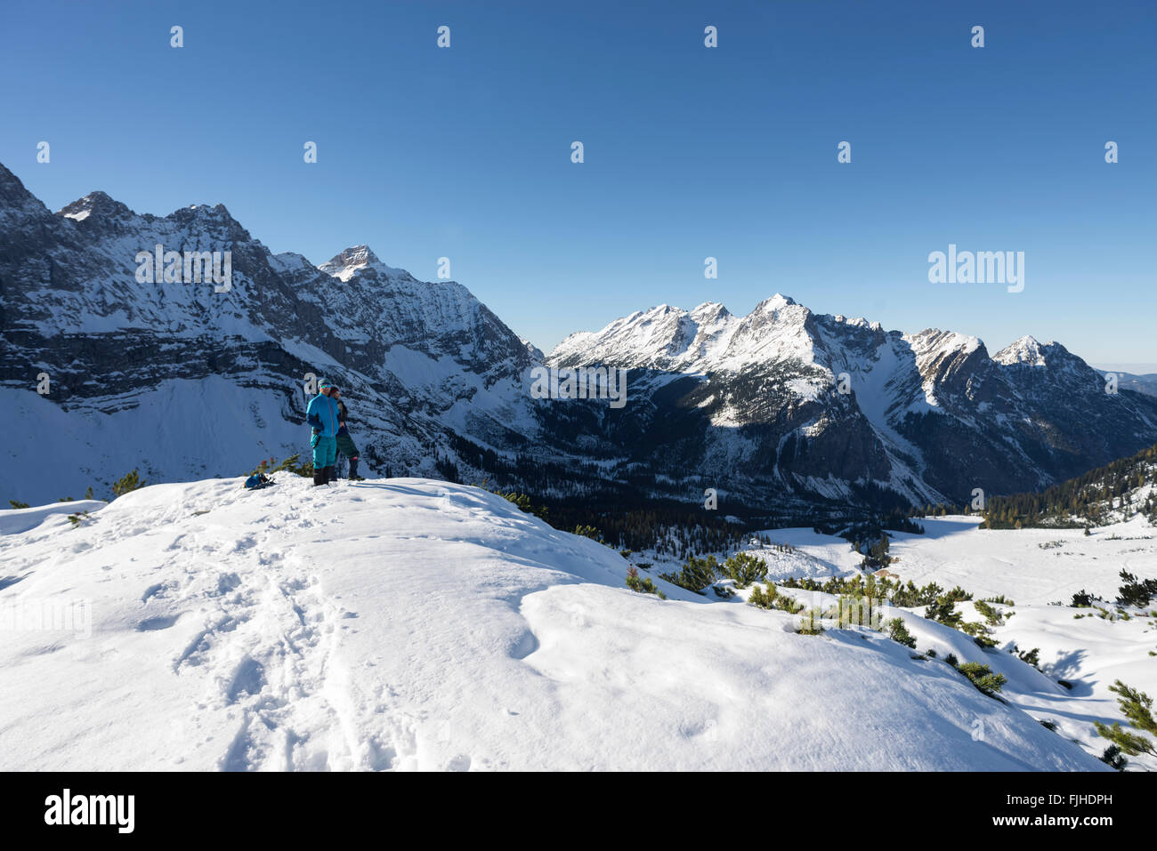 Les randonneurs se tenant sur la montagne enneigée en regardant les montagnes du Karwendel et le petit Ahornboden dans plein soleil, Tirol, Autriche Banque D'Images