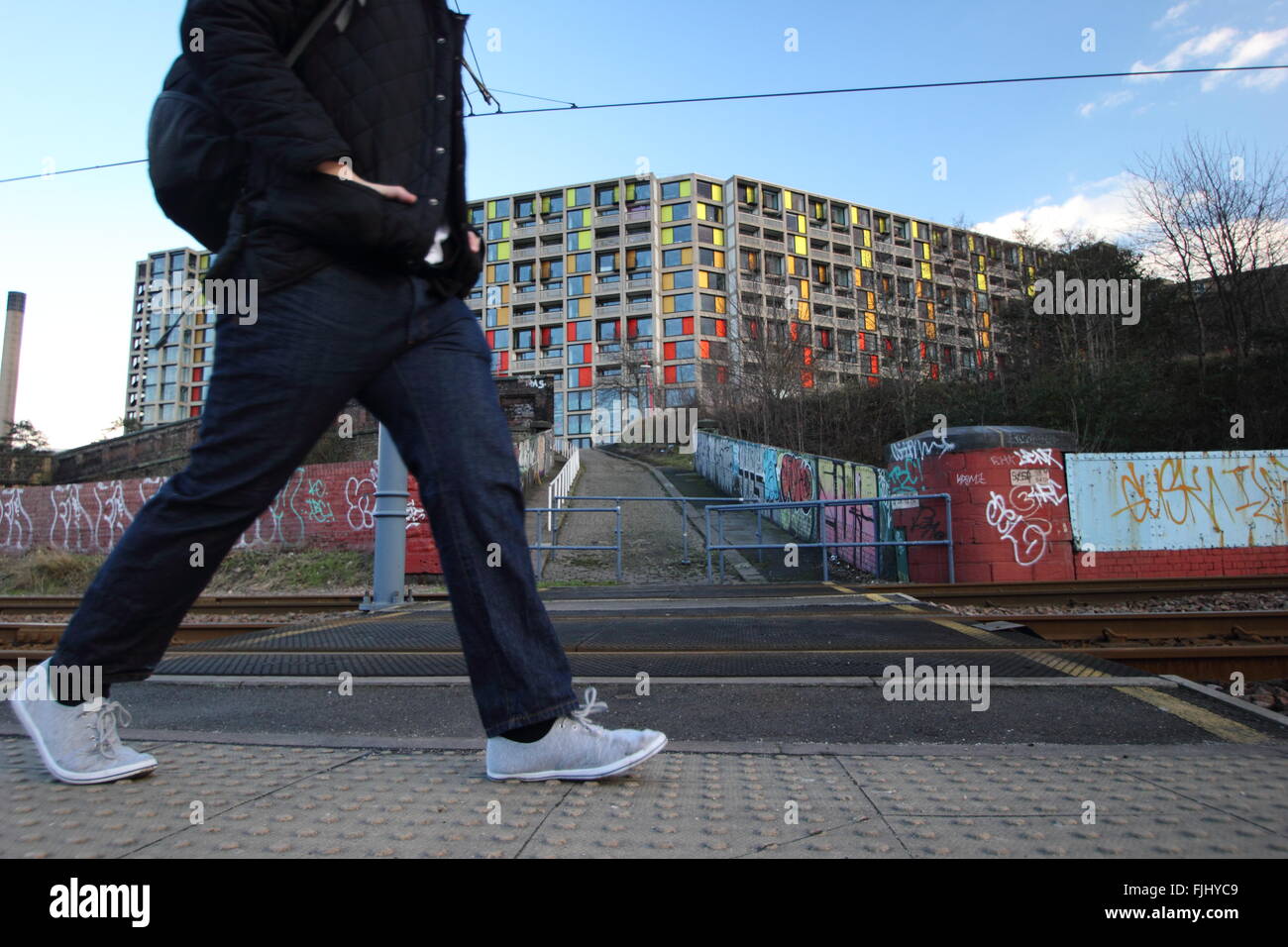 Un homme marche par le tramway près de Park Hill housing estate (photo) dans le centre de la ville de Sheffield, Yorkshire UK Banque D'Images