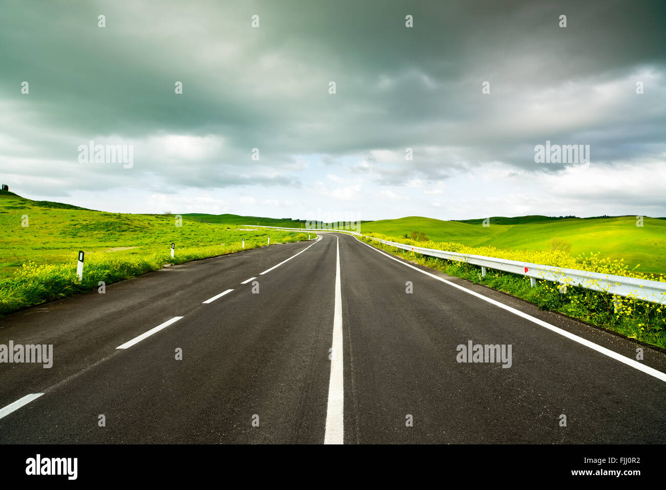 La toscane, route droite du paysage rural de la Toscane avec champ jaune et vert. Collines près de Volterra, Italie. L'Europe. Banque D'Images